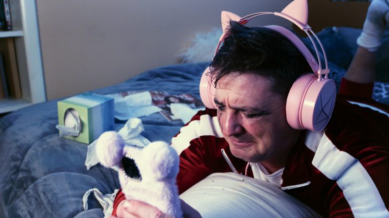 Chaos dressed up like a teen girl with pink headphones, a pink phone case, and mascara tears running down his face.