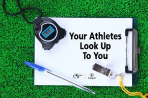 white clipboard on grass with stopwatch pen and whistle