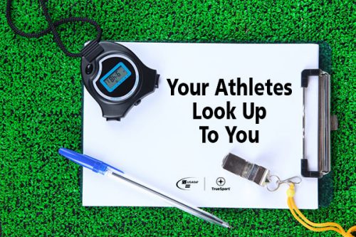 white clipboard on grass with stopwatch pen and whistle