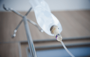 An IV bag of fluid hanging from a metal stand.
