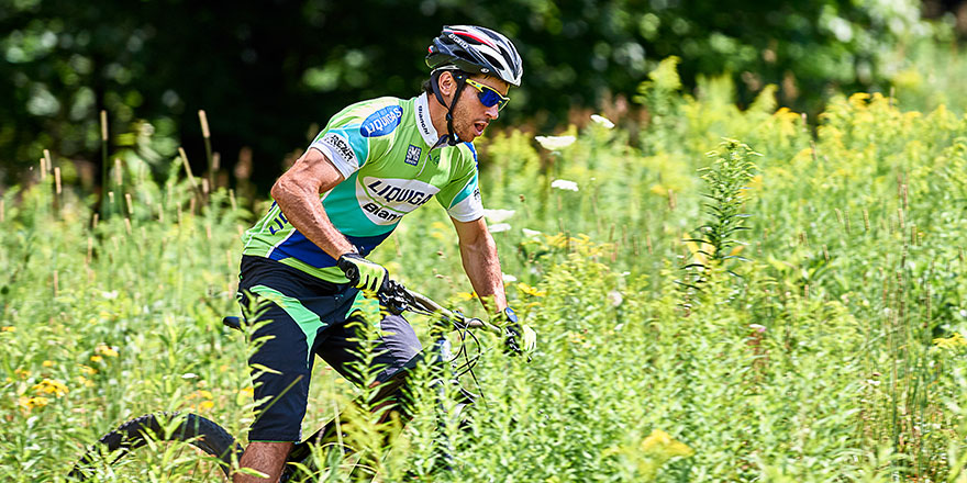 Noah Hoffman riding his bike on a grassy field.