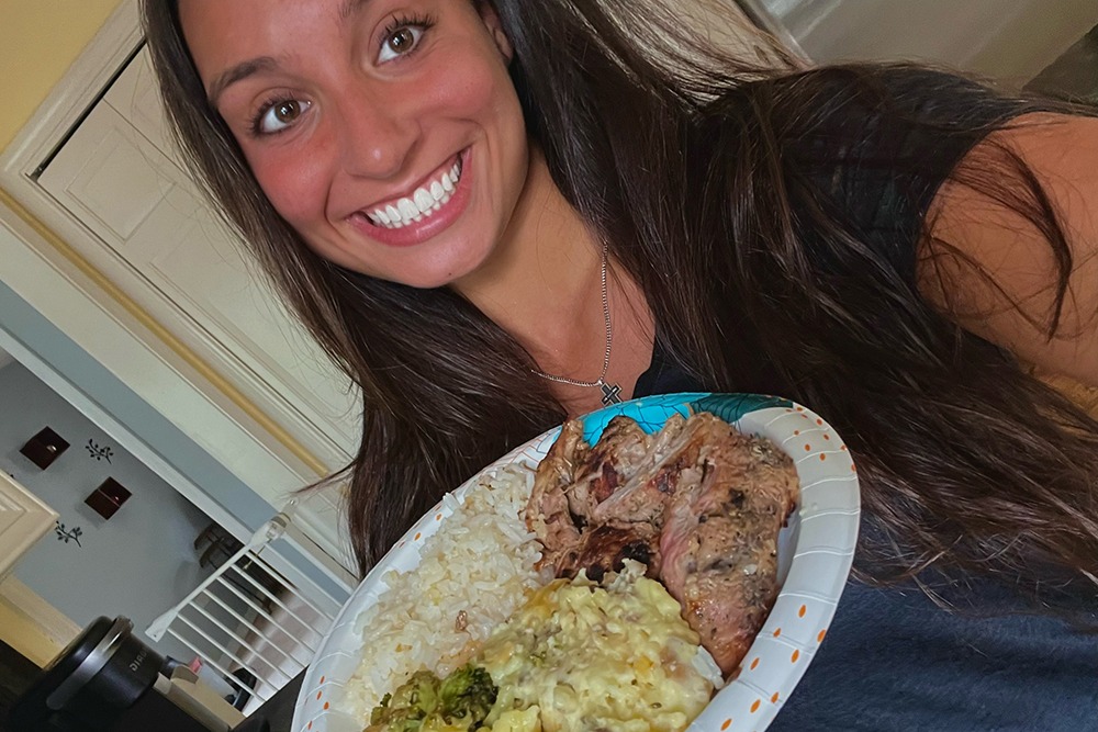 Abby Raymond holding a plate of rice, pork, and broccoli.