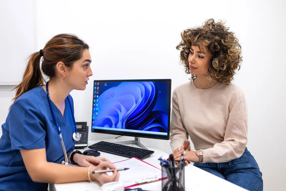 Woman consulting with a medical professional at a desk.