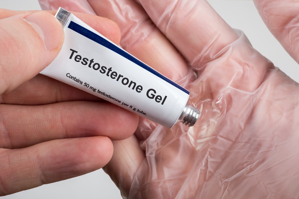 Hand holding a tube of testosterone gel.