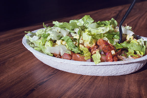 Burrito bowl filled with lettuce, rice, veggies, and beans.