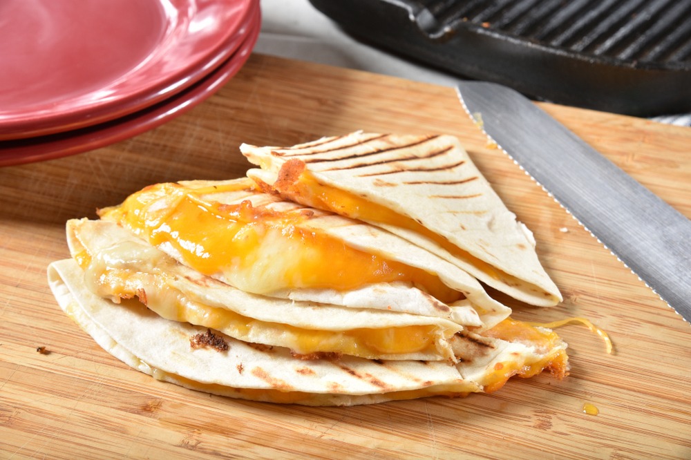 A cheese quesadilla next to a knife.