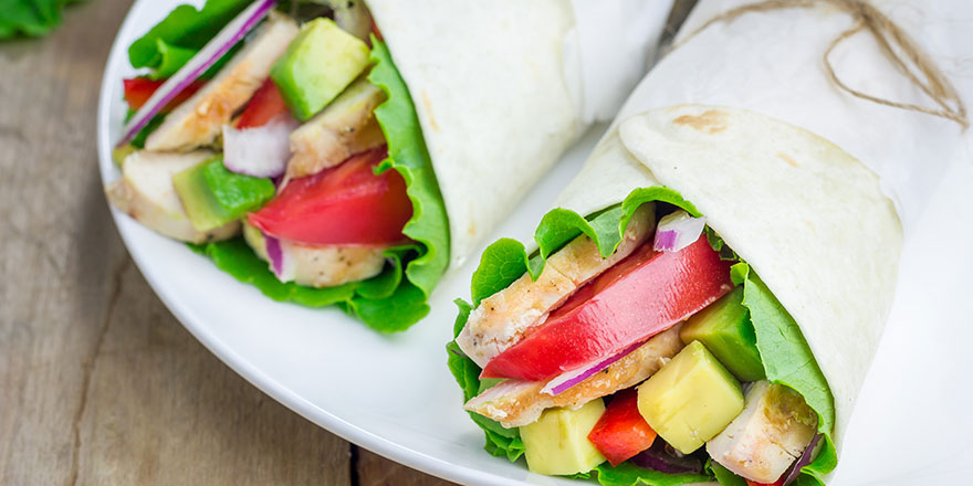 Chicken wrap with vegetables and lettuce in a tortilla.