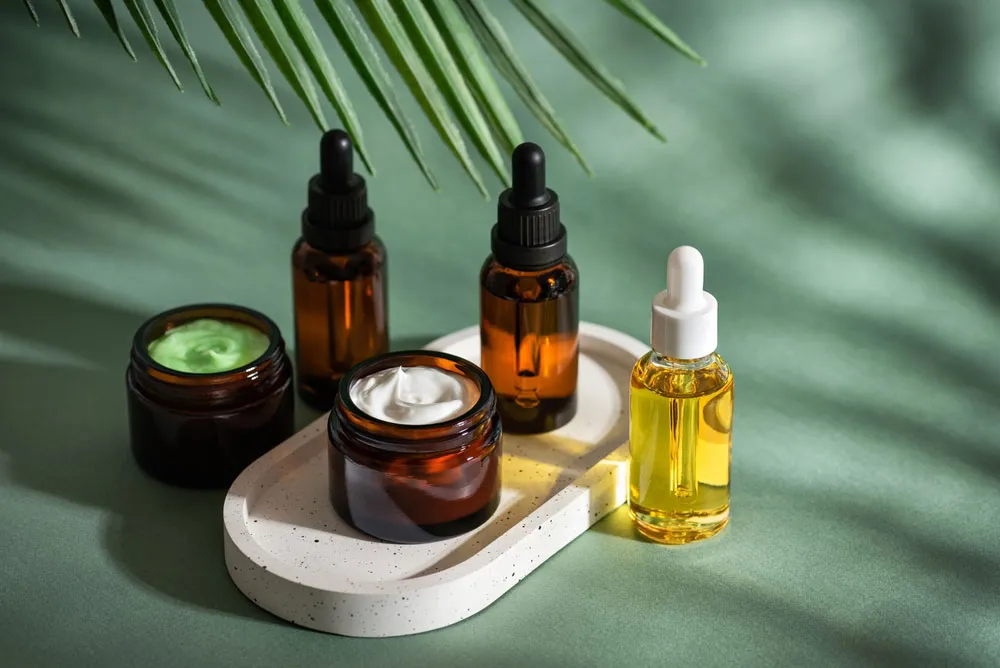 Unlabeled creams and serums on a green background.
