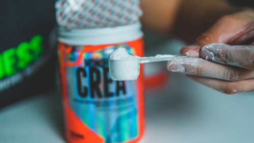 Close up of a hand holding a scoop of powdered supplement.