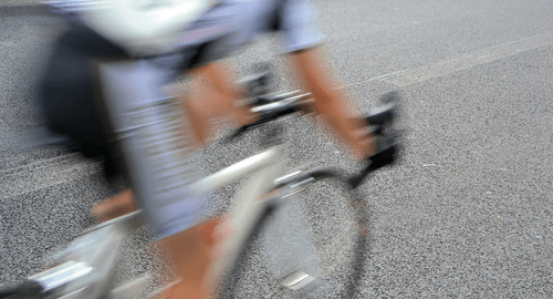 A cyclist moving by so quickly they are blurred.