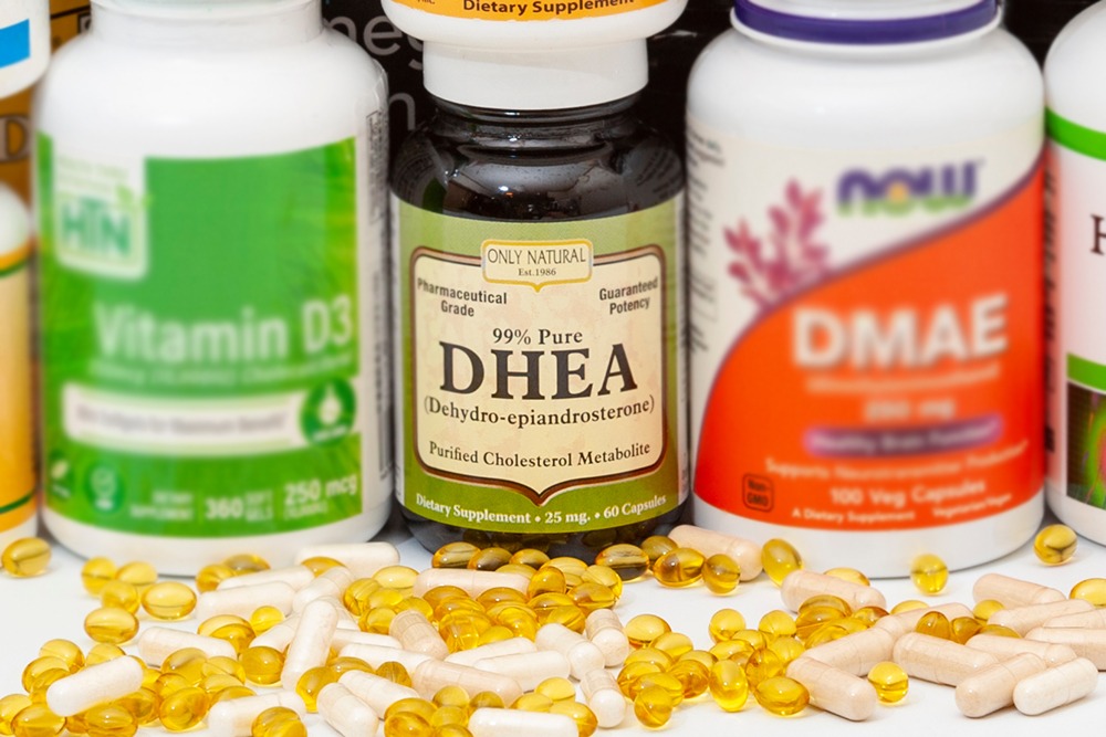 DHEA Supplement bottle with various pills next to the bottle.