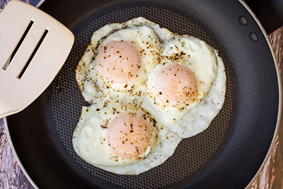 three eggs over easy in a pan