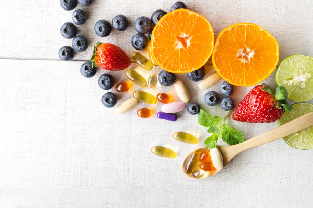 Fresh fruits on a table next to supplement pills.