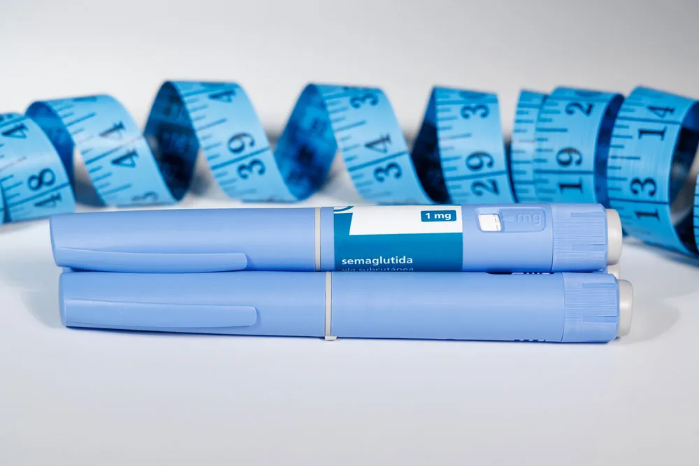 Two GLP-1 injectables next to a measuring tape.