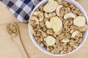 white bowl full of granola and sliced banana