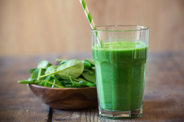 green smoothie with a straw on a table.