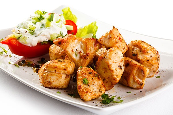 grilled chicken nuggets next to a stuffed tomato.