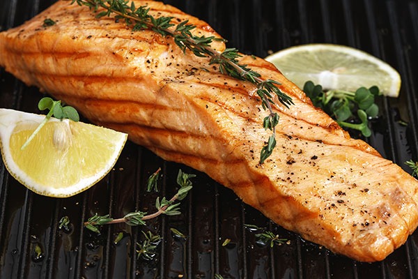 Grilled salmon next to sliced lemon.