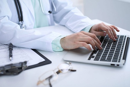 doctor at desktop computer typing on keyboard