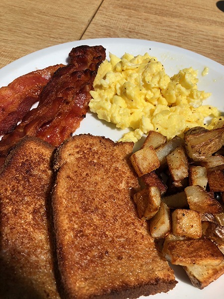 Plate of eggs, toast, bacon, and potatoes.