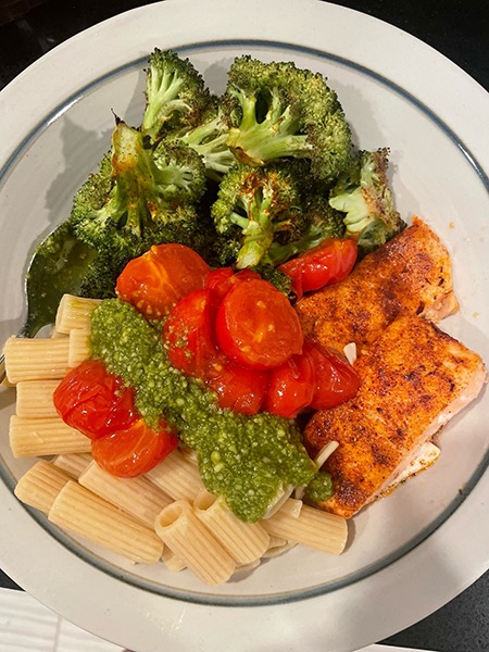 A plate of pesto salmon, salmon, broccoli, and roasted tomatoes.