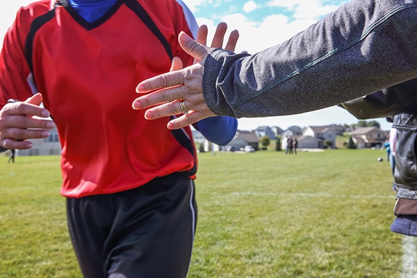 Young athlete high fiving a parent on the sideline (close-up of hands.)