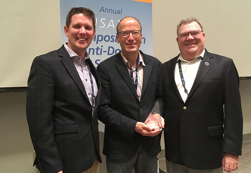 Matt Fedoruk, Matthis Kamber, and Larry Bowers standing together with an award for Matthis.