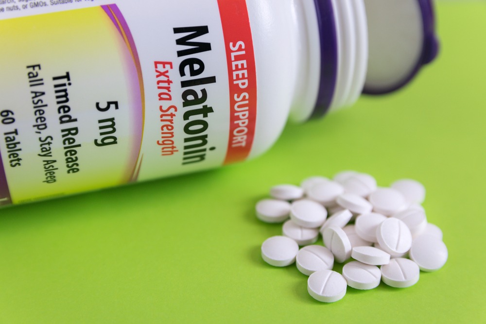 melatonin supplement bottle and pills.