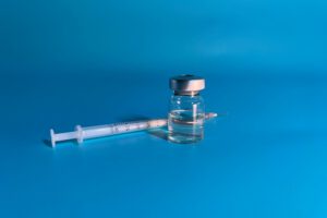 Peptide container next to a syringe.