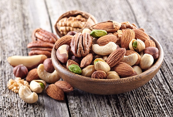 Various raw nuts in a wood bowl.