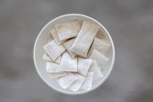A round container full of small white pouches to be dissolve in the mouth.