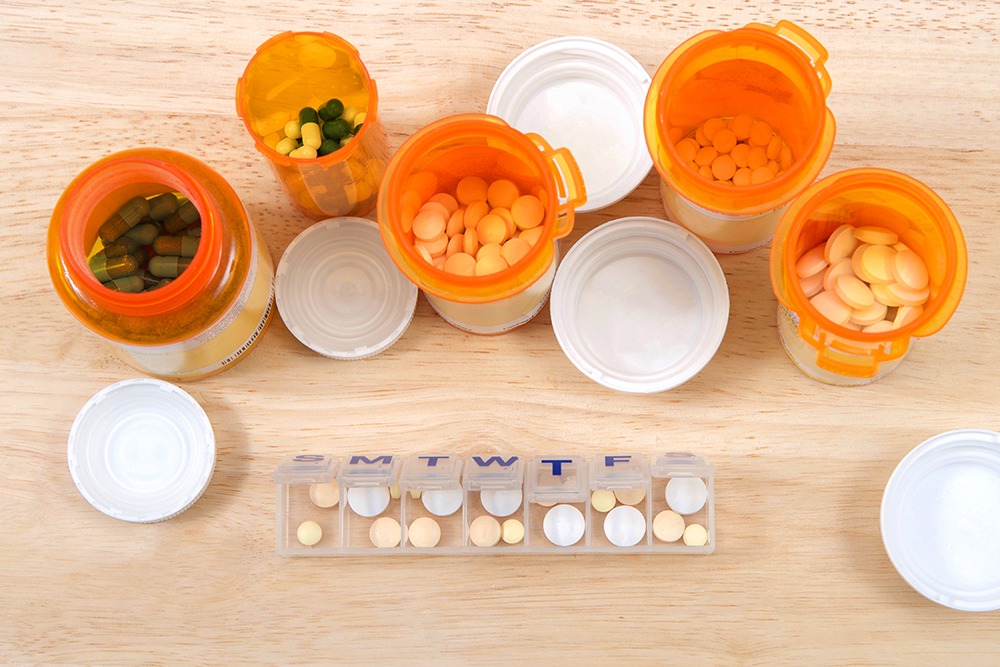 A variety of prescription medication bottles and a pill organizer.