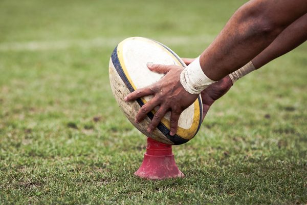 Man setting up a rugby oval to kick.