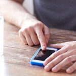 pills and glass of water on table while person scrolls through phone