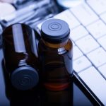 Glass vials next to a computer keyboard.