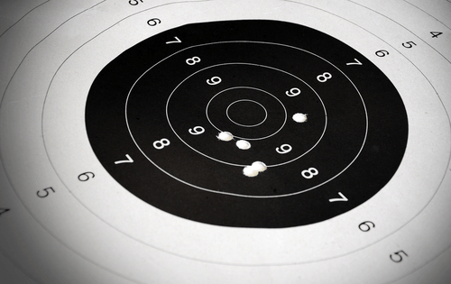 image of paper target full of bullet holes