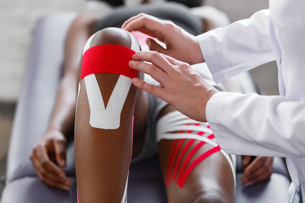 Health professional applying take to an athlete's leg.