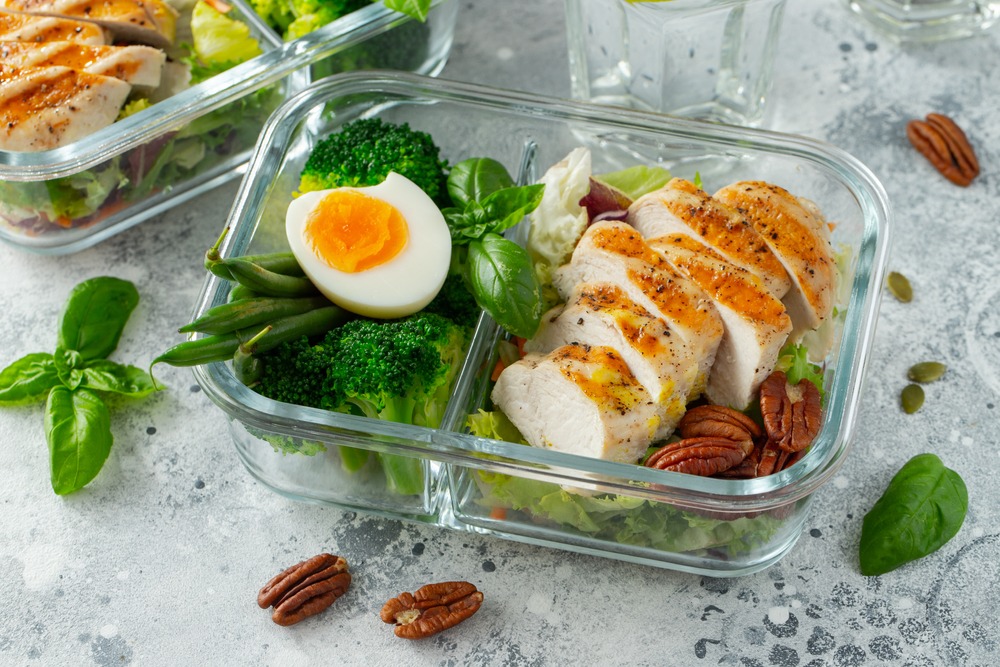 Prepped meal with chicken, egg, nuts, and greens.