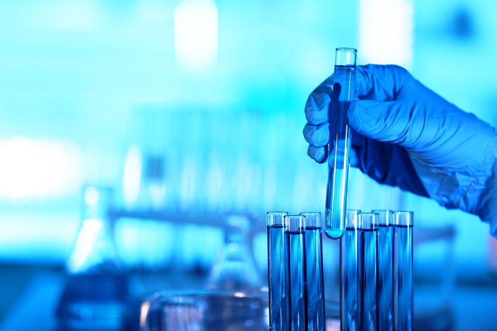 Gloved hand holding a vial in medical setting.