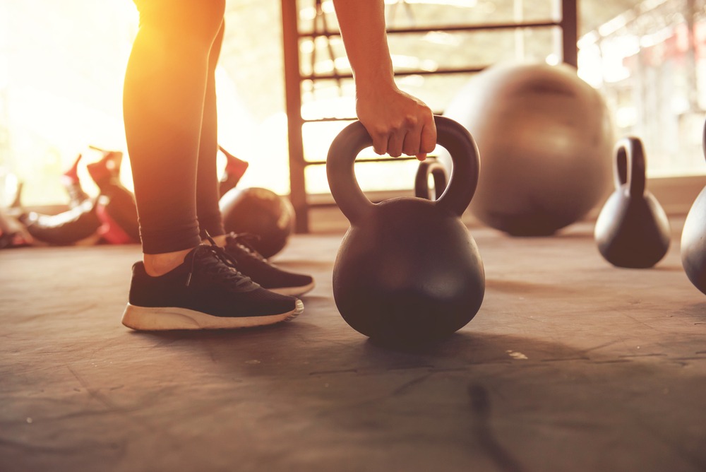 Close up of hands on a kettle bell in a gym.