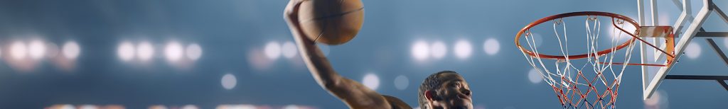 A male basketball player making a slam dunk.