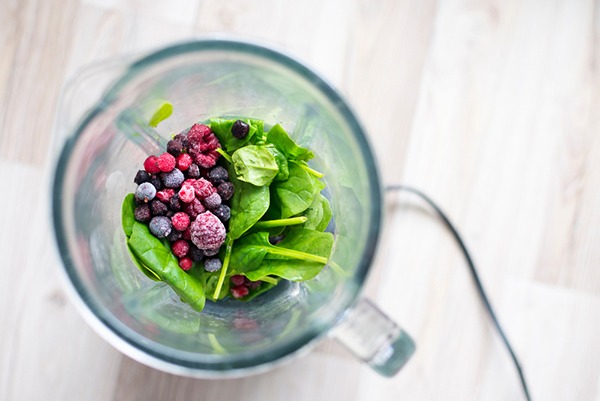 Shot fro above of spinach and frozen berries in a blender.