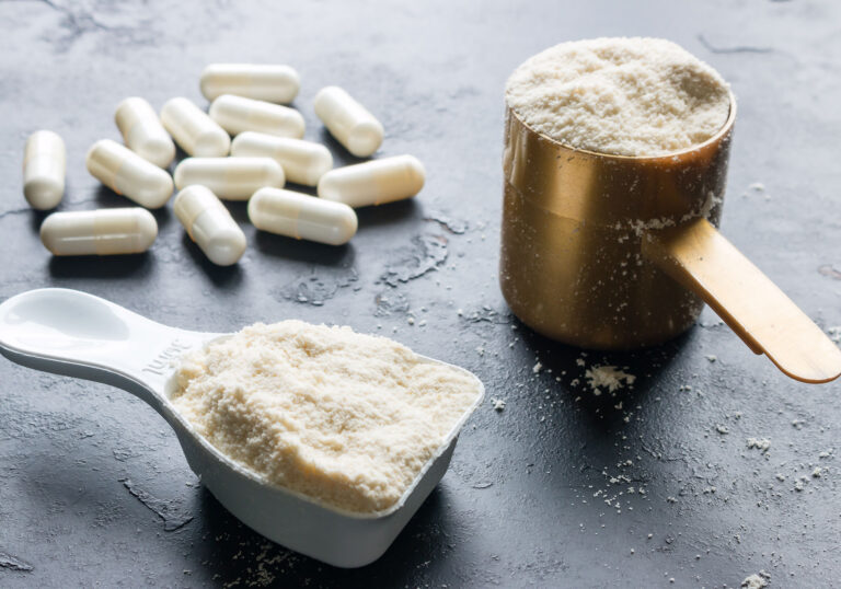 powdered supplements in two different cups and a handful of white pills