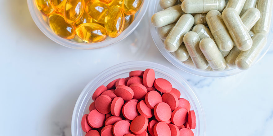 Three bowls of different colored and sized pills.