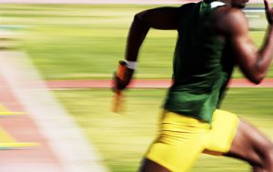 a track athlete running past quickly with a baton 