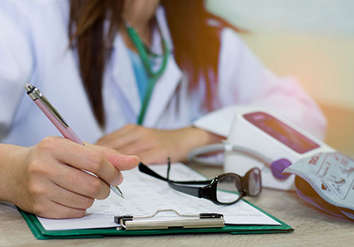 Female doctor writing on a clipboard