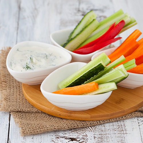 Bowl of dip next to three bowls of cut up raw vegetables.