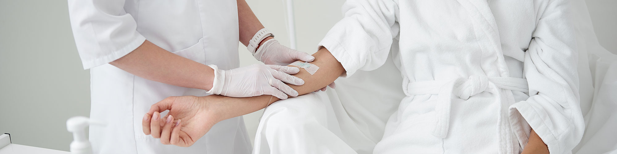 woman in robe receiving IV infusion at wellness clinic