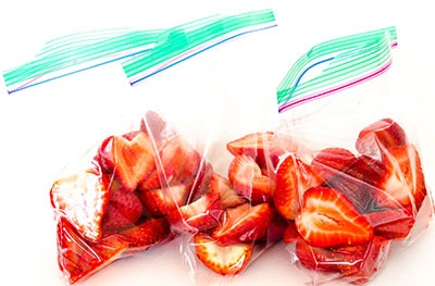 three plastic bags full of sliced strawberries